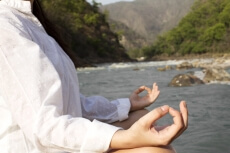 side view of a girl meditating alongside river
