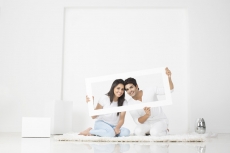 couple posing with frame in new home  