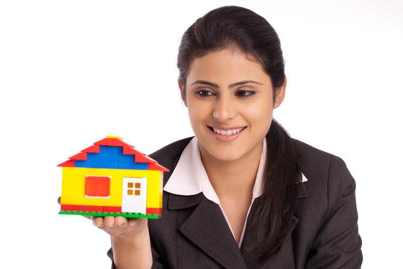 beautiful young businesswoman holding small house model against white