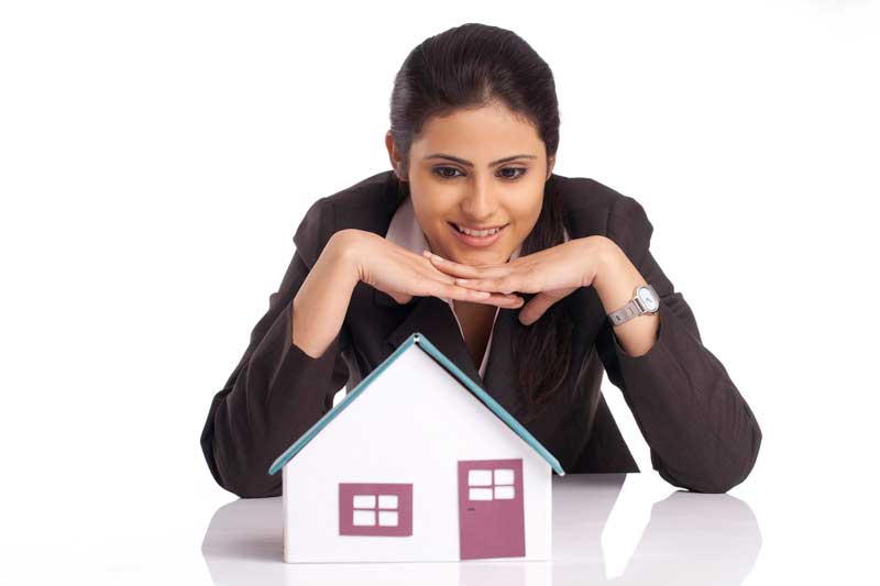 young businesswoman leaning on a small house model