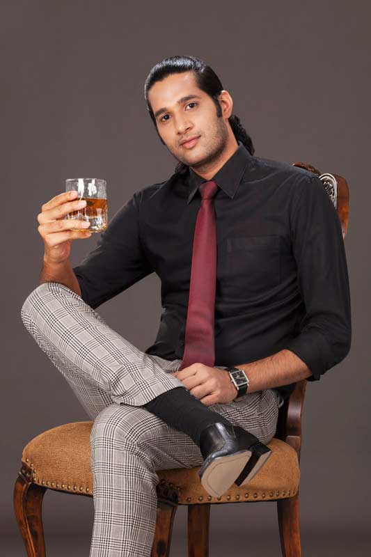 man in formals posing with a drink 