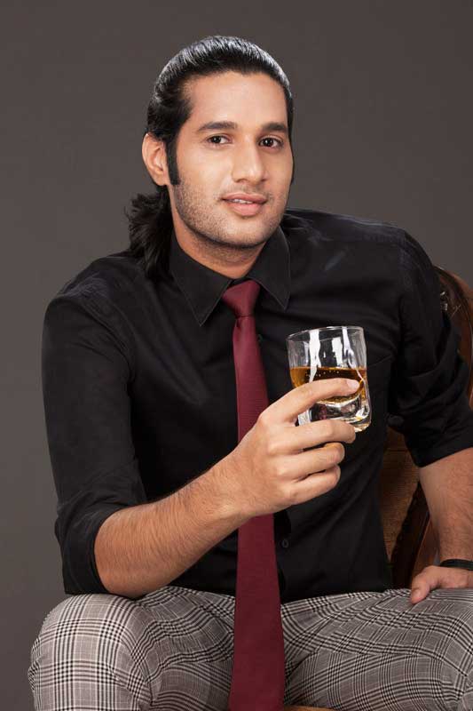 young business guy holding a drink and sitting on a chair