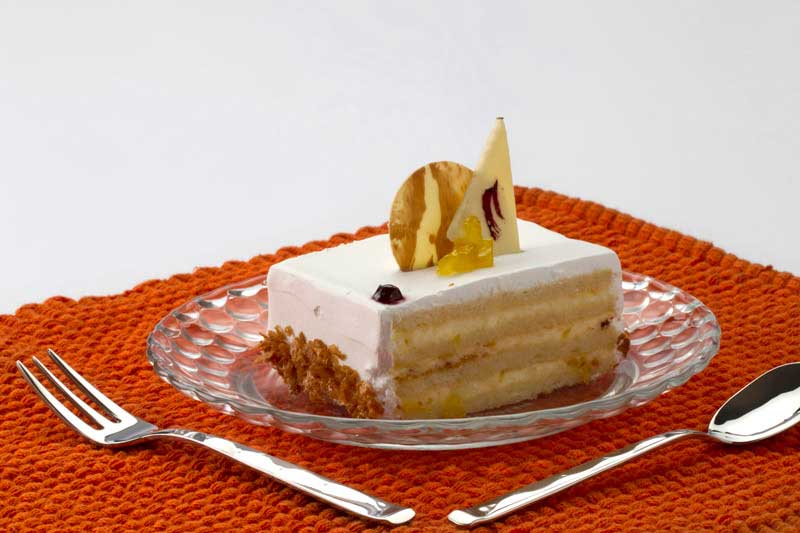 a piece of cream cake served on a plate with white background  