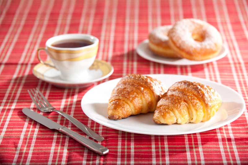 sugar coated donuts served with a croissant and black tea