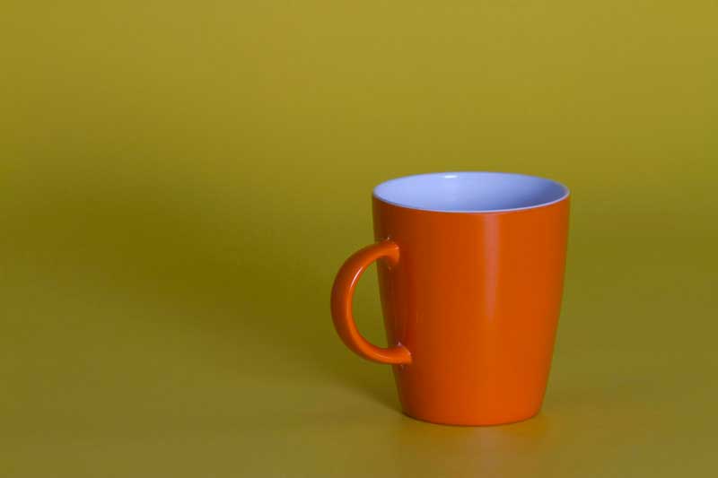 orange coffee cup against yellow background