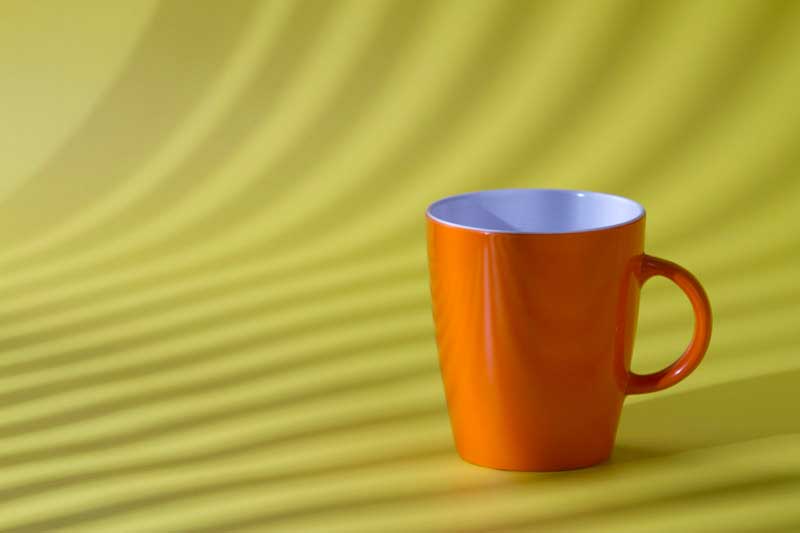 orange coffee cup isolated on yellow background