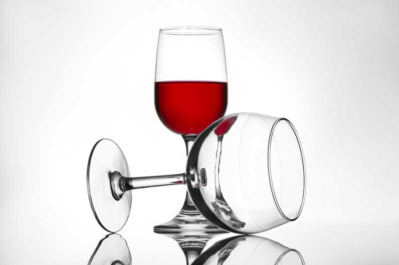 full and empty pair of red wine glasses