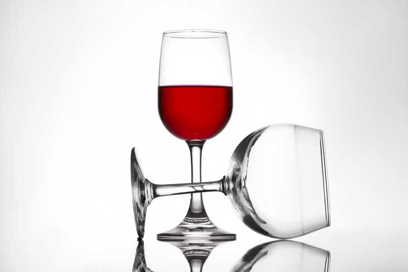 full and empty pair of red wine glasses
