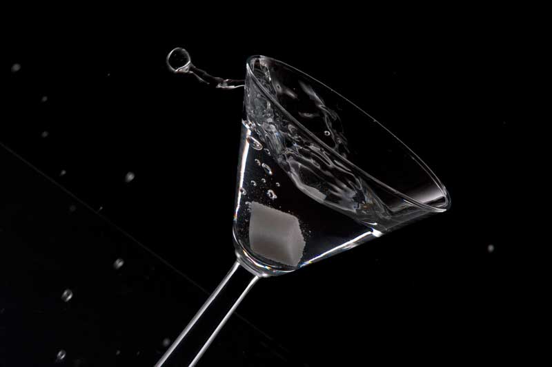 a glass of martini in motion against dark background 