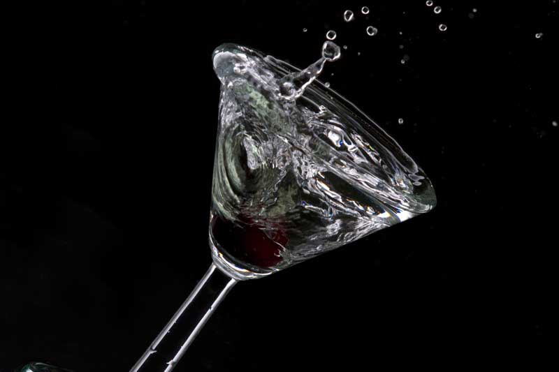 close up of a cocktail drink with a cherry in motion