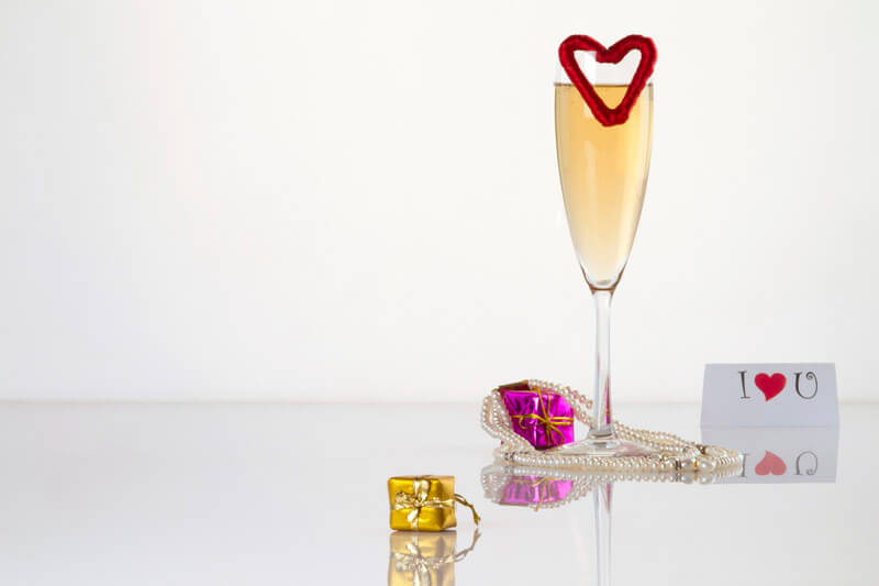 a glass of champagne shot with some gift miniatures and a love note on
