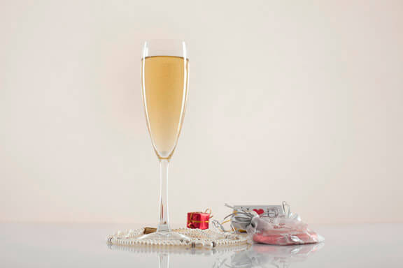 a glass of champagne on white background with gifts around 