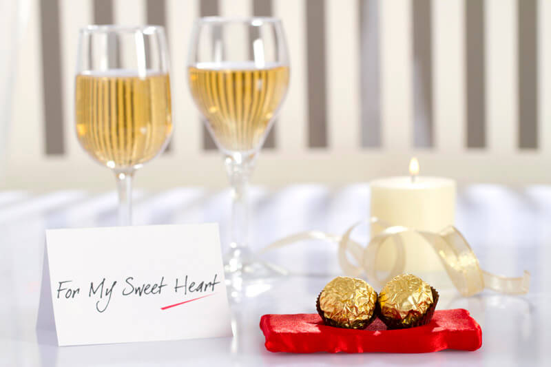 table decorated with chocolates,champagne,love note and scented candle