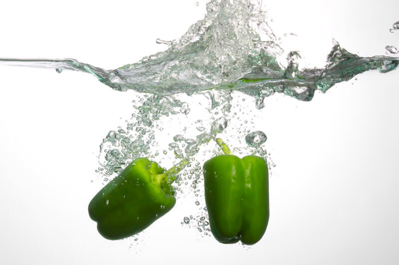 two fresh green capsicum in water