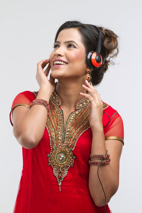 indian girl in red designer suit listening to music