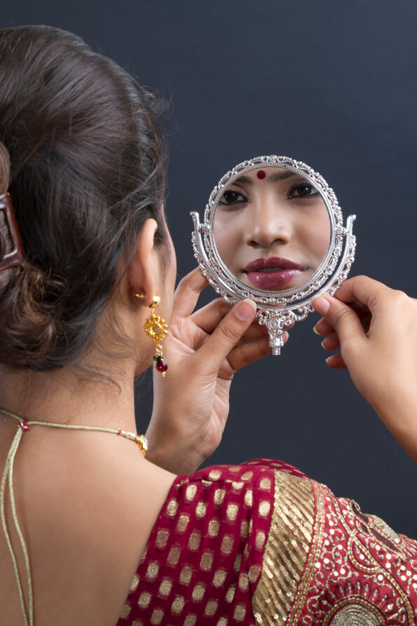 indian bride smiling at reflection in mirror wearing necklace