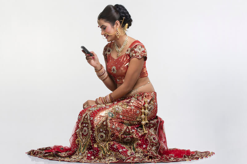 indian bride in bridal wear looking into mobile phone 