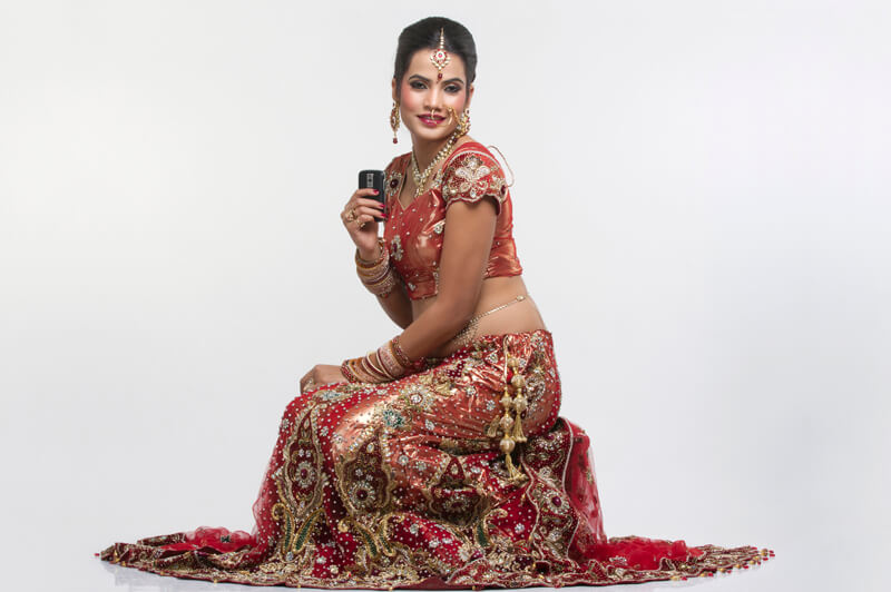 indian bride in bridal wear with mobile phone 
