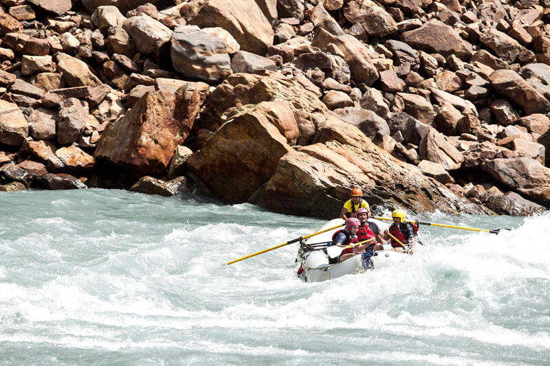 men sailing through rapids while rafting