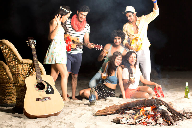 a group of six people singing and dancing on the sand