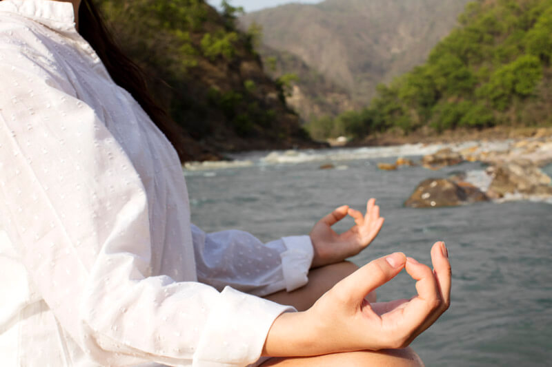 side view of a girl meditating alongside river