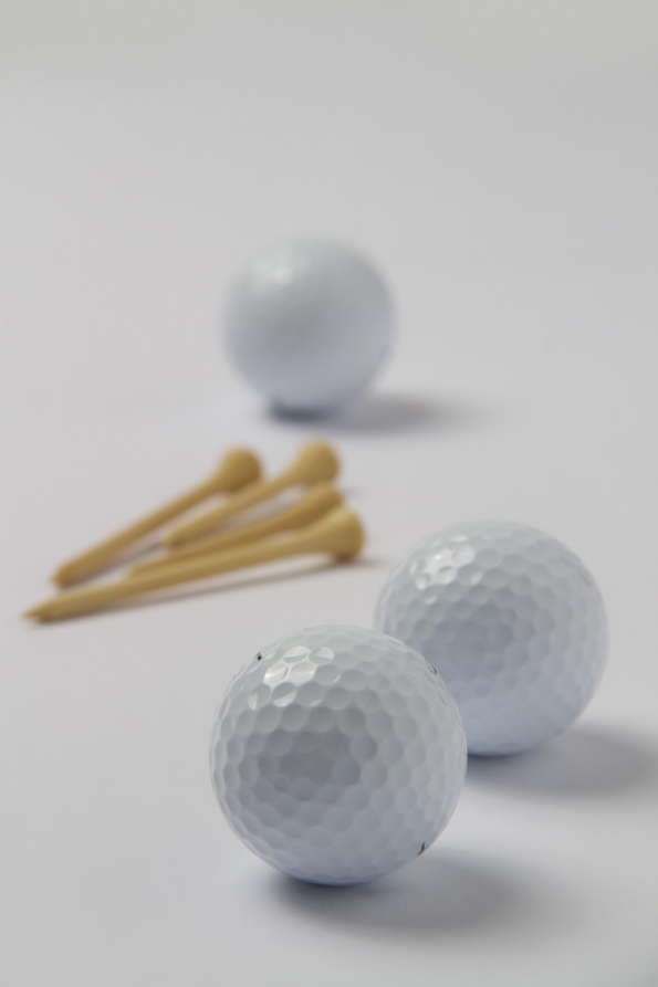 close up shot of golf balls and ball pins 
