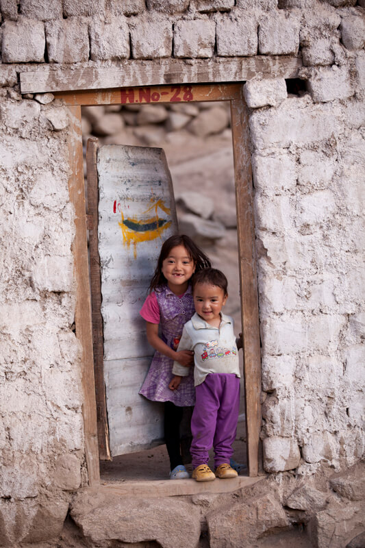 siblings standing at the doorway in leh ladakh