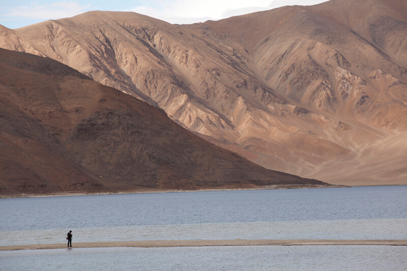 beautiful scenic view of desert mountains and a man standing on river 