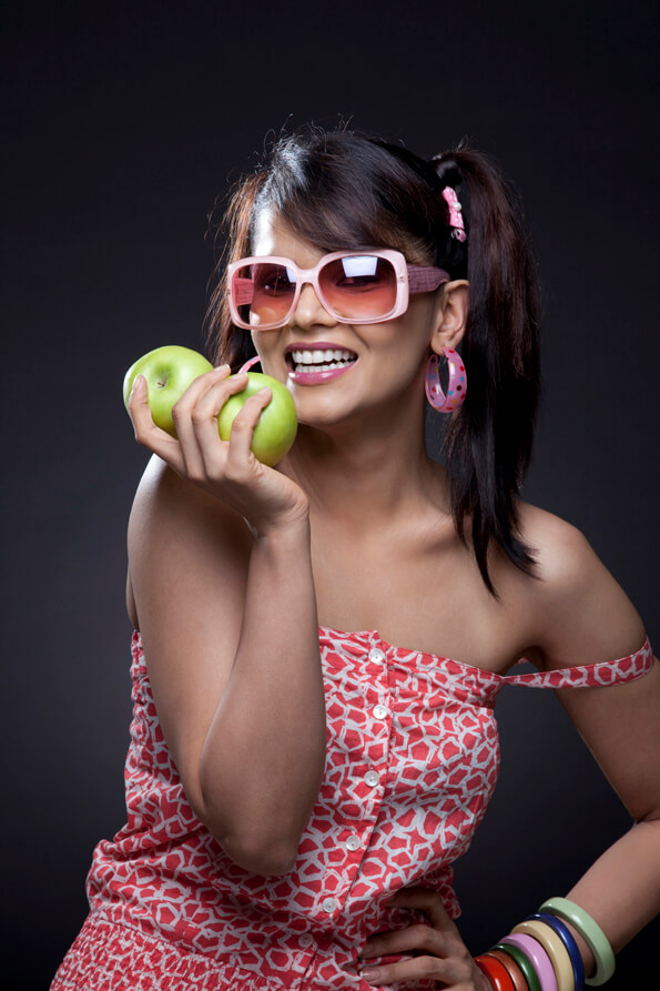 young teenager in cool shades holding two fresh green apples