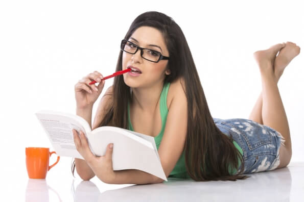 girl wearing specs and posing with a book against a white background