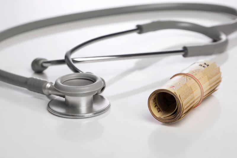 rolled cash with stethoscope on white background