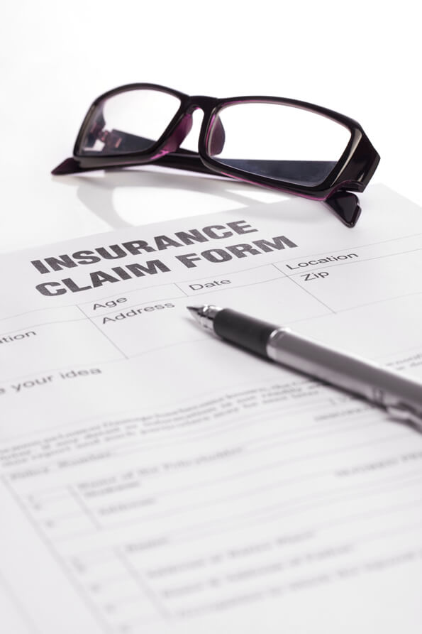 insurance claim form with a pen and specs on table  