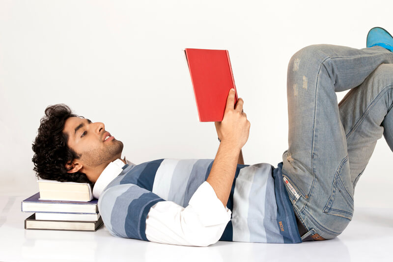 college boy reading book while lying down