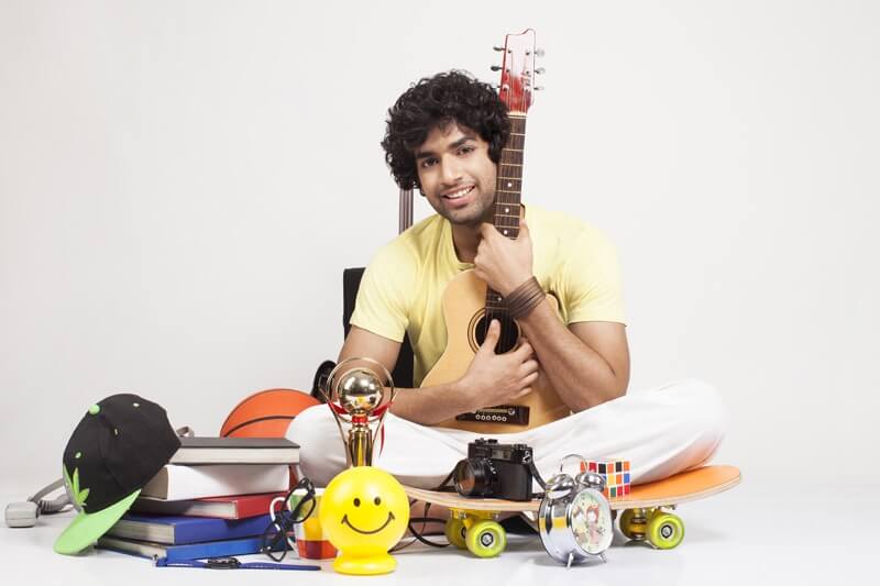 boy holding a guitar and posing with things around him 