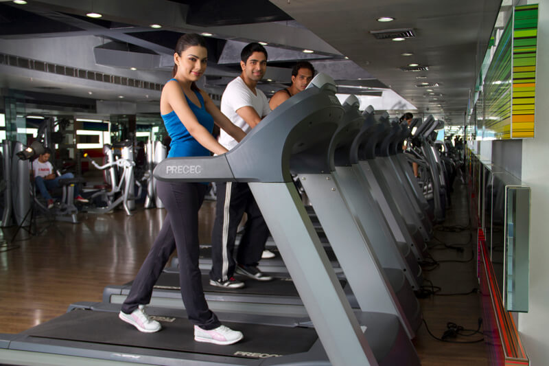 side view of three people walking on the treadmill