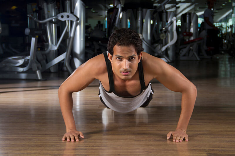 young teenager in a vest doing push ups on the floor