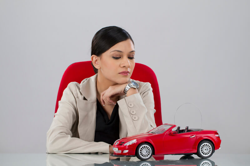 business woman in looking at miniature of sports car