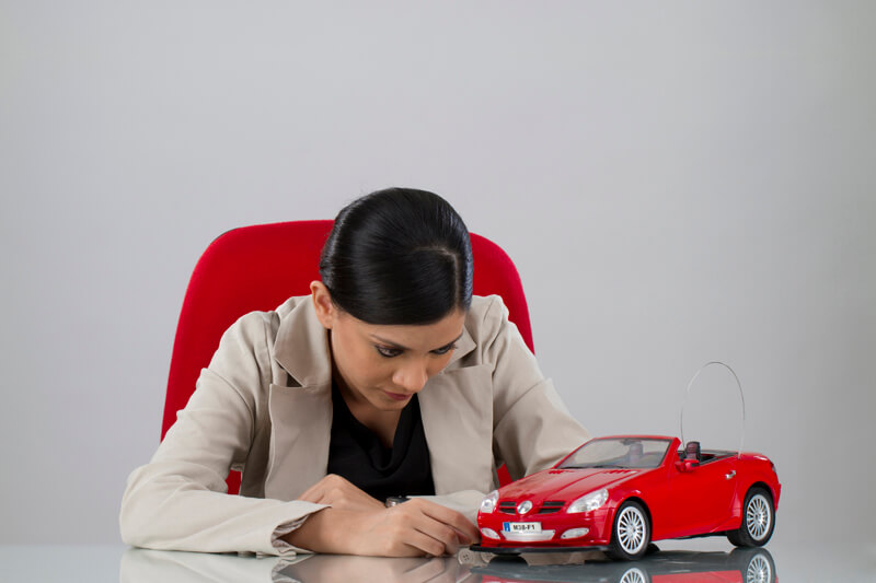 woman sitting at her office desk staring at the toy car on her table