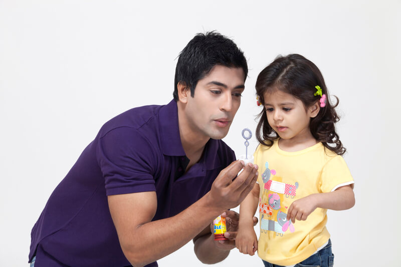 father teaching his daughter how to blow bubbles