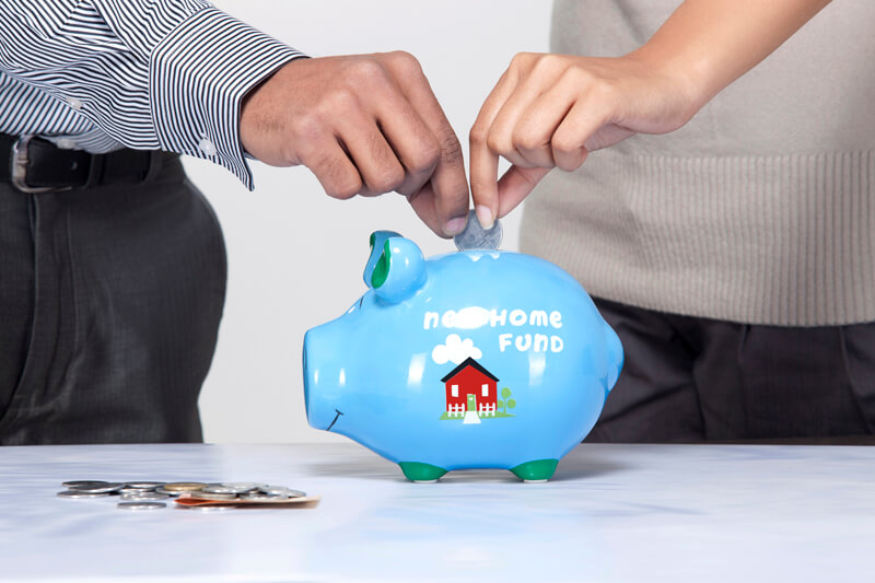 close-up of a couples hand dropping coin in a piggy bank