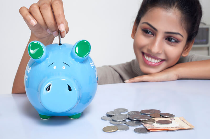 woman dropping coins in a piggy bank