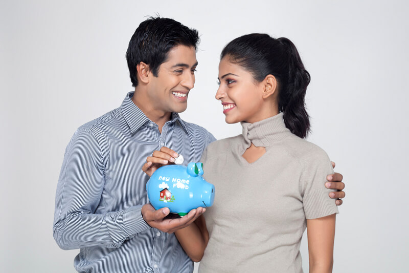 couple smiling at each other holding piggy bank