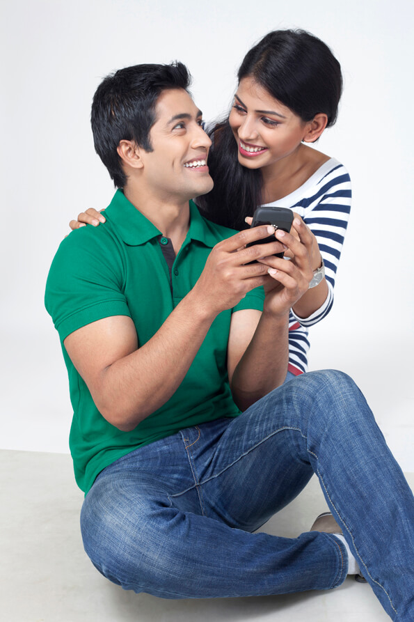 attractive couple smiling holding a cellphone