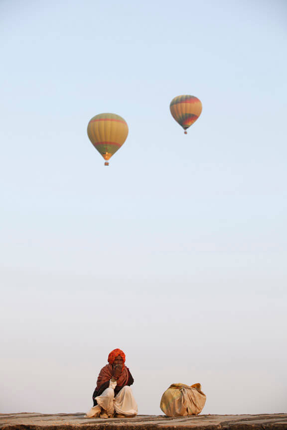 rural man sitting with hot air balloons in background 