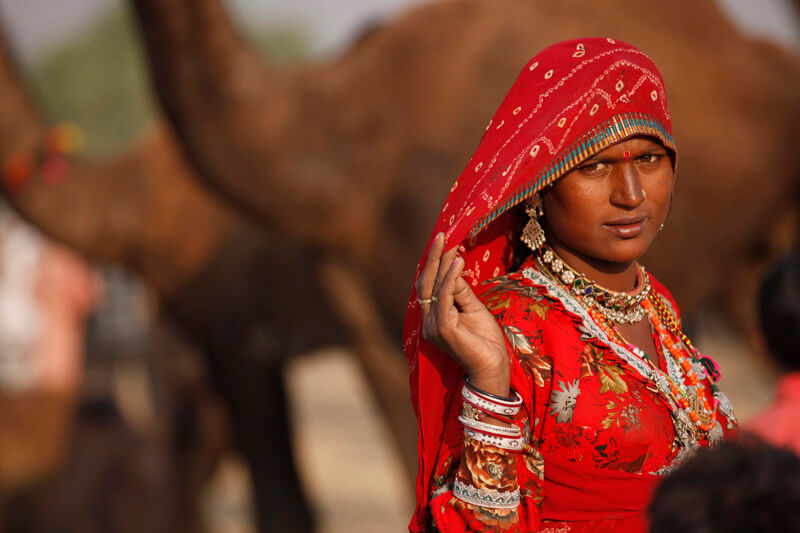 village woman standing against the background of camels
