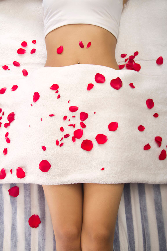 body of a girl lying on bed with flower petals 