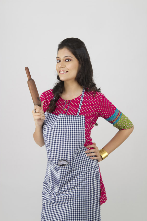 young girl smiling and posing with rolling pin