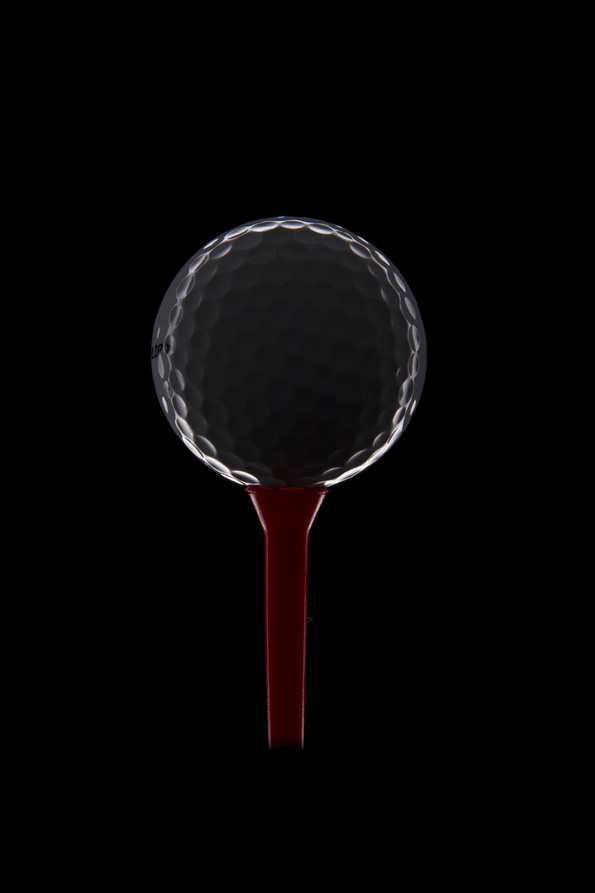 golf ball on golf tee with dark background 