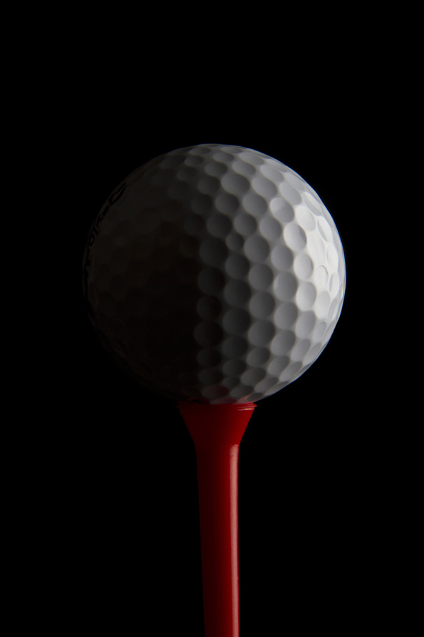 golf ball on a golf tee with dark background 