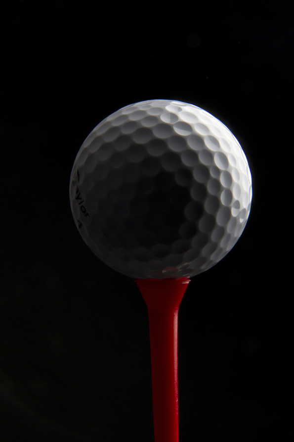 golf ball on a golf tee against dark background